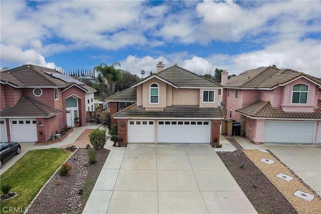 view of front of property with a tiled roof, an attached garage, a chimney, and driveway