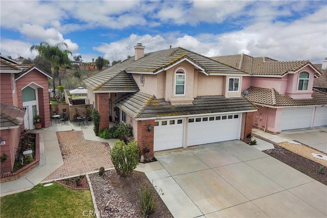 traditional home with brick siding, an attached garage, a tile roof, a chimney, and driveway