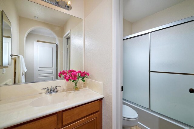 bathroom with enclosed tub / shower combo, toilet, and vanity