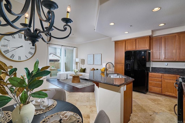 kitchen featuring dark stone countertops, black fridge, stainless steel stove, brown cabinetry, and a sink