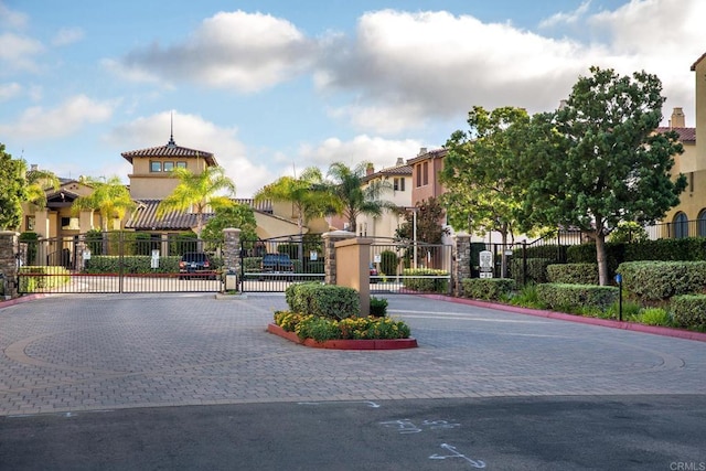 view of road featuring curbs, a residential view, a gated entry, and a gate