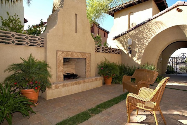 view of patio / terrace featuring exterior fireplace and fence