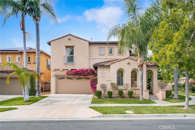 mediterranean / spanish house with stucco siding, an attached garage, driveway, and a tiled roof