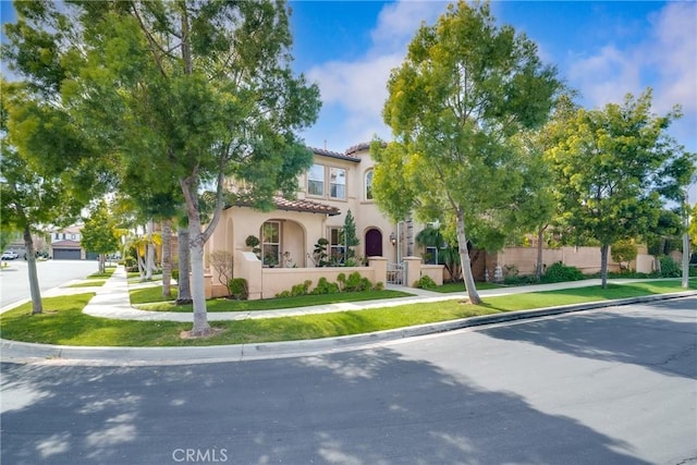 view of front of property featuring a tile roof, a fenced front yard, and stucco siding