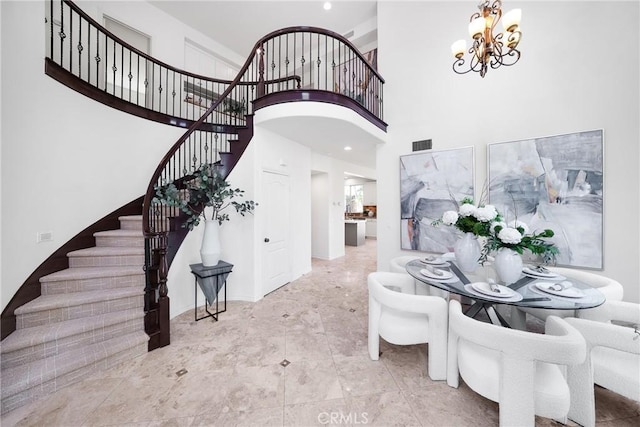 entrance foyer with visible vents, a notable chandelier, a high ceiling, and stairs