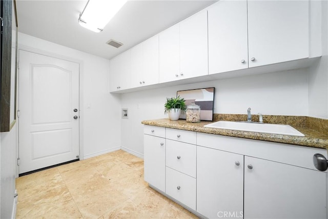 clothes washing area featuring baseboards, visible vents, cabinet space, a sink, and washer hookup