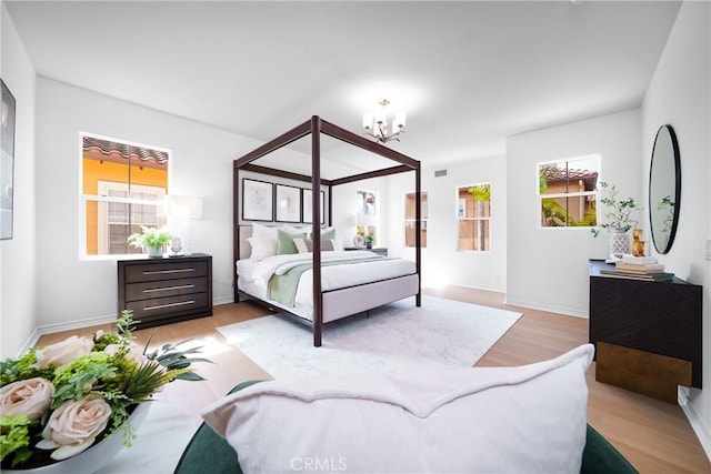 bedroom featuring a notable chandelier, light wood-style flooring, and baseboards