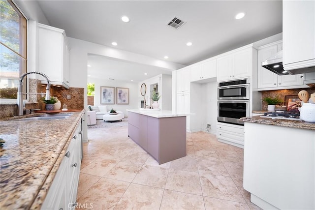 kitchen with visible vents, white cabinetry, stainless steel appliances, and a sink