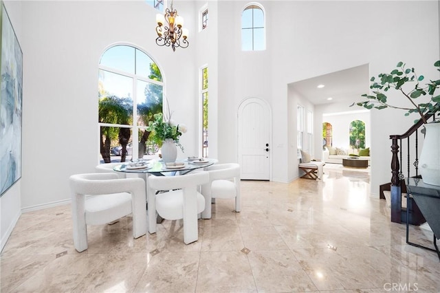 dining area with a wealth of natural light, a notable chandelier, and marble finish floor