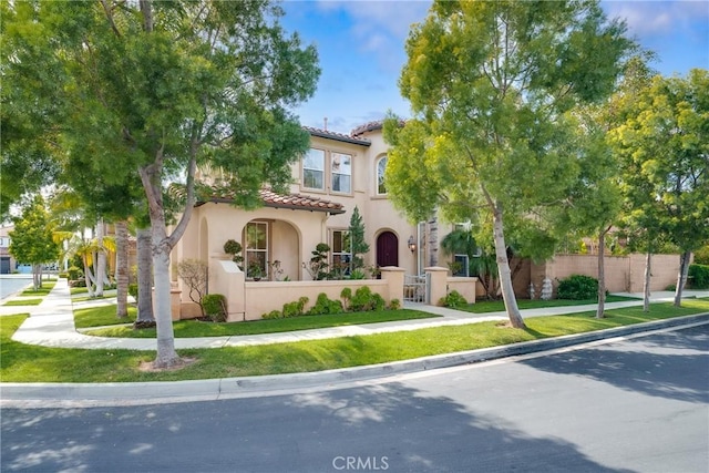 view of front of property featuring a fenced front yard, a tile roof, and stucco siding