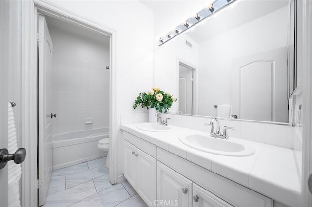 full bath featuring double vanity, marble finish floor, toilet, and a sink