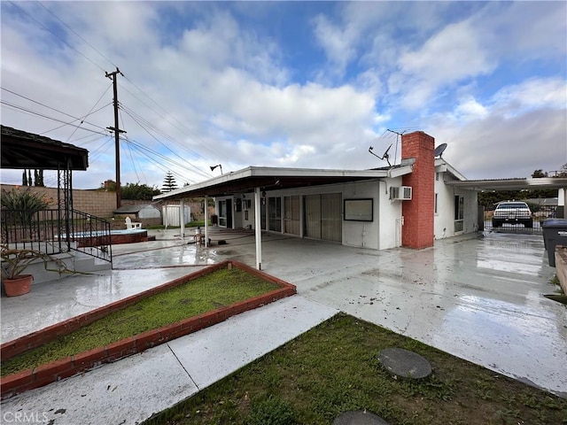 back of house with a chimney, a wall mounted air conditioner, a patio, and fence