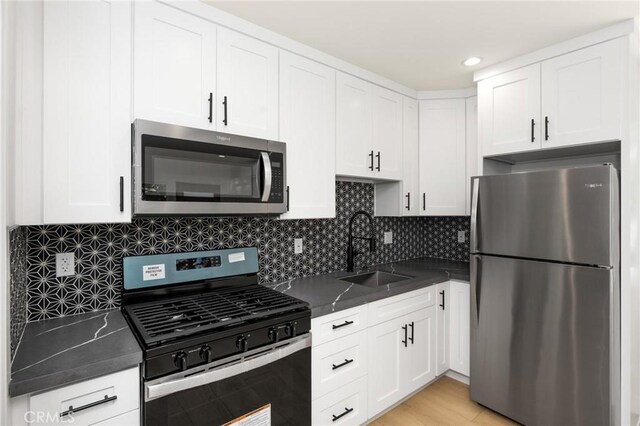914 N Catalina St, Burbank, CA 91505 - kitchen with appliances with stainless steel finishes, a sink, dark countertops, white cabinets, and tasteful backsplash