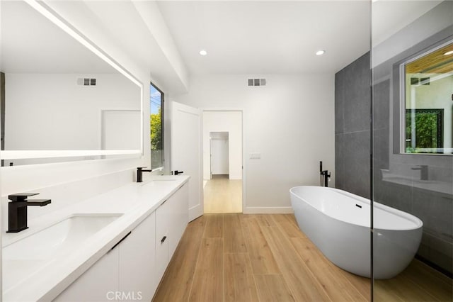 914 N Catalina St, Burbank, CA 91505 - bathroom with a freestanding tub, wood finished floors, double vanity, recessed lighting, and baseboards