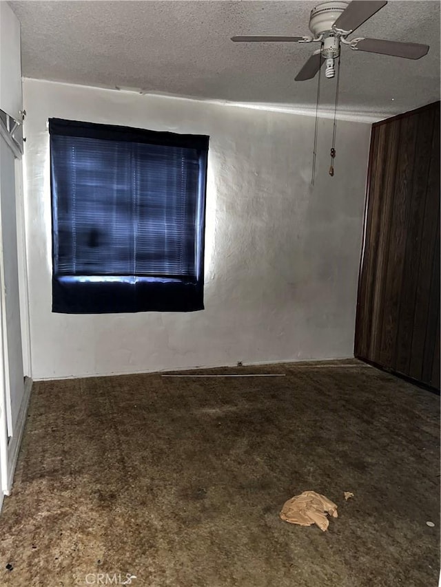 spare room featuring a textured ceiling, carpet, and a ceiling fan