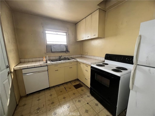 kitchen with white appliances, tile countertops, light floors, a sink, and cream cabinets