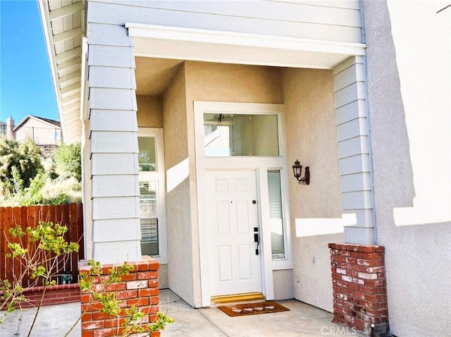 entrance to property with stucco siding and fence