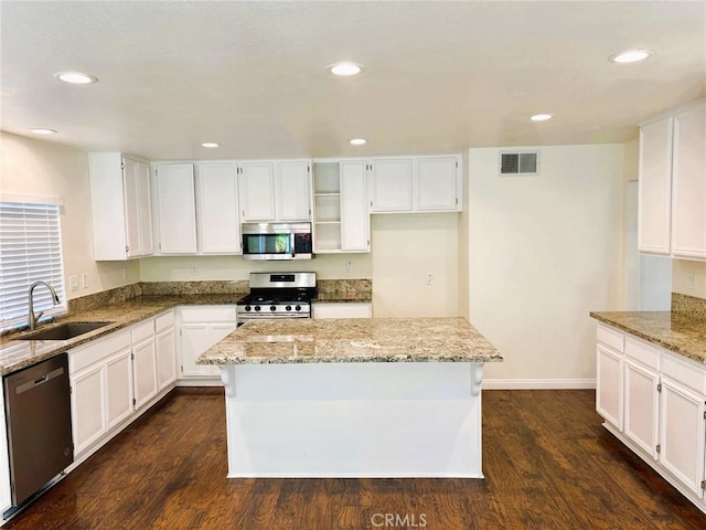 kitchen with light stone counters, visible vents, dark wood finished floors, a sink, and stainless steel appliances