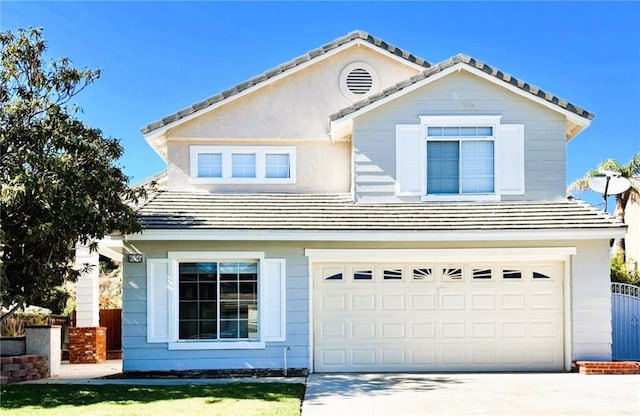 view of front of home featuring a tile roof, an attached garage, concrete driveway, and fence