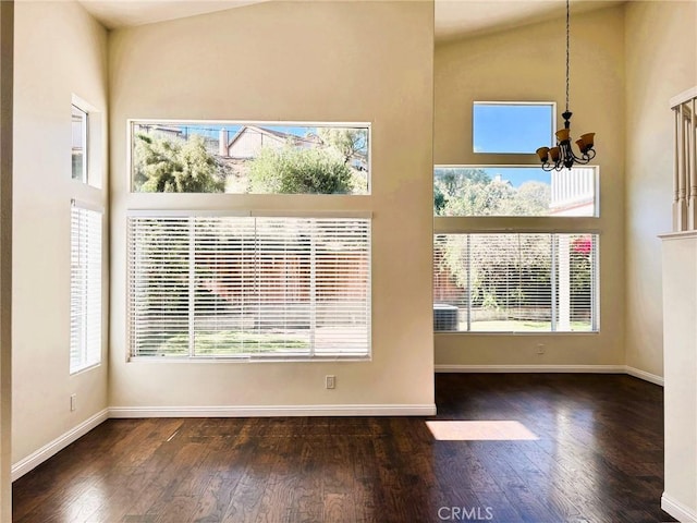 interior space with a wealth of natural light, an inviting chandelier, hardwood / wood-style floors, and a towering ceiling