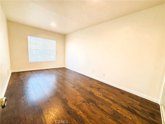 spare room with baseboards and dark wood finished floors