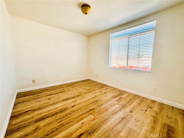 empty room with baseboards and hardwood / wood-style flooring