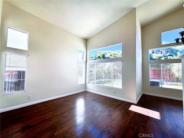 unfurnished room with a wealth of natural light, high vaulted ceiling, baseboards, and wood-type flooring