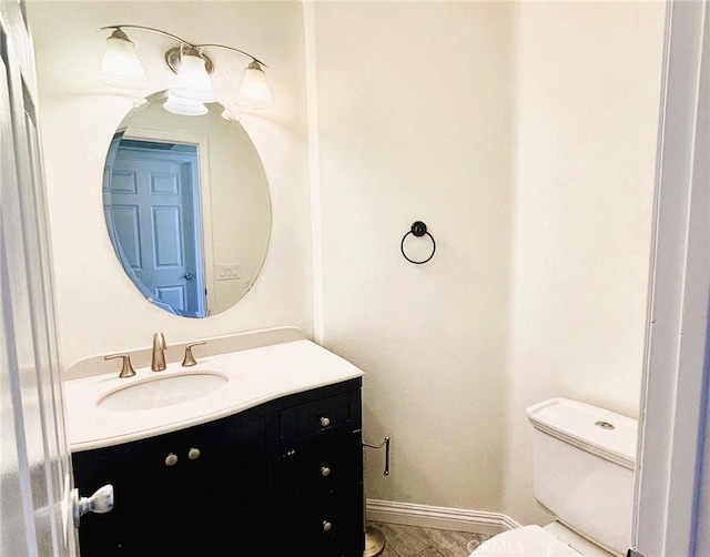 half bathroom featuring vanity, toilet, and baseboards