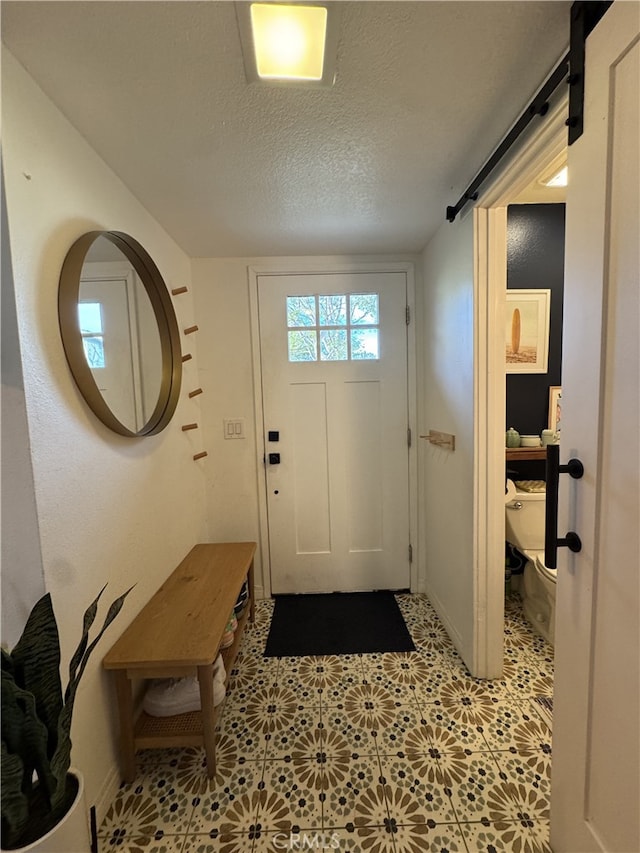 entryway featuring a barn door, a textured ceiling, and light floors