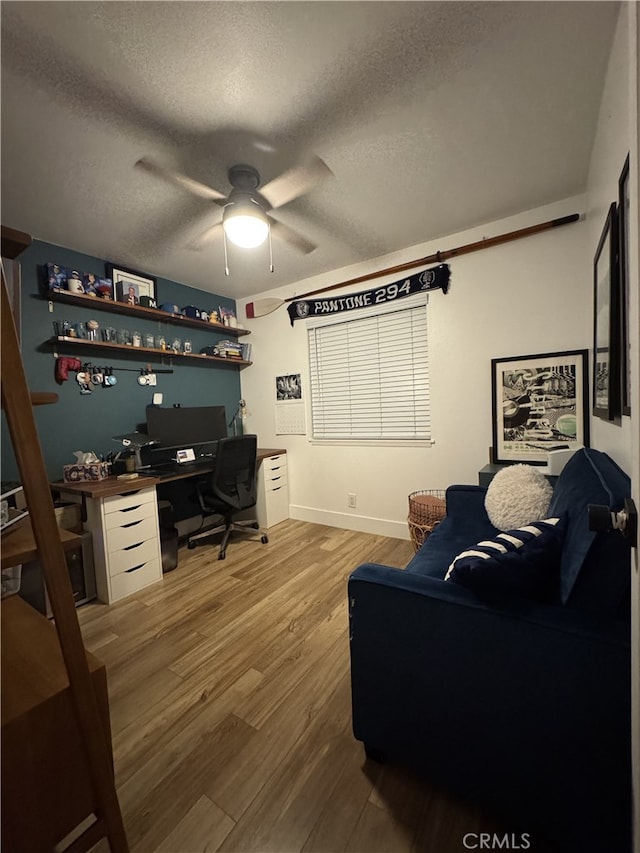 office featuring a ceiling fan, light wood finished floors, and a textured ceiling