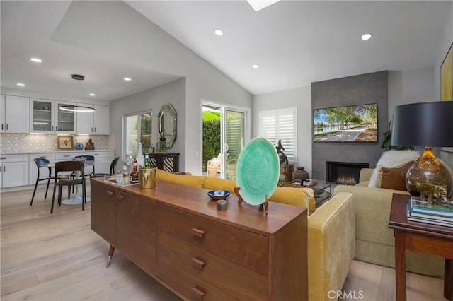 living area with recessed lighting, light wood-style flooring, a large fireplace, and lofted ceiling