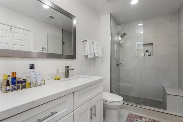 bathroom with vanity, toilet, visible vents, and a tile shower