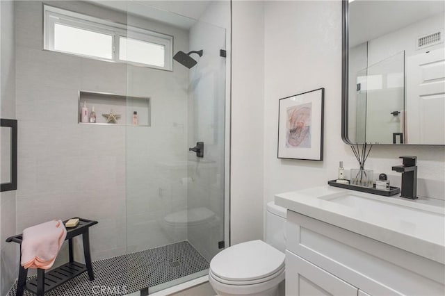 full bath featuring vanity, toilet, visible vents, and a stall shower