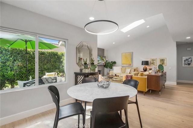 dining area with lofted ceiling with skylight, recessed lighting, baseboards, and light wood finished floors