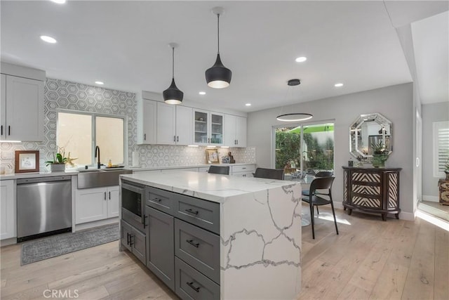 kitchen with light wood-style flooring, white cabinetry, stainless steel appliances, and a sink