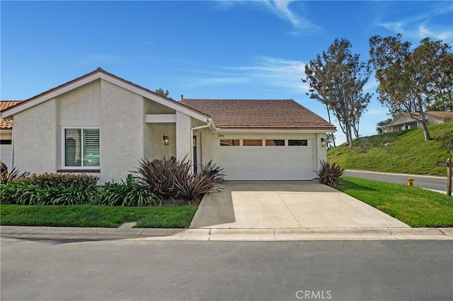 view of front of home featuring a tile roof, an attached garage, driveway, and stucco siding