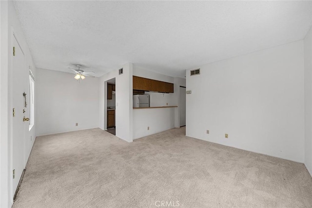 unfurnished living room with visible vents, a textured ceiling, a ceiling fan, and carpet floors