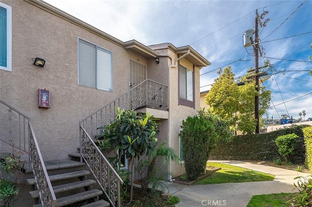 view of side of property featuring stairway and stucco siding