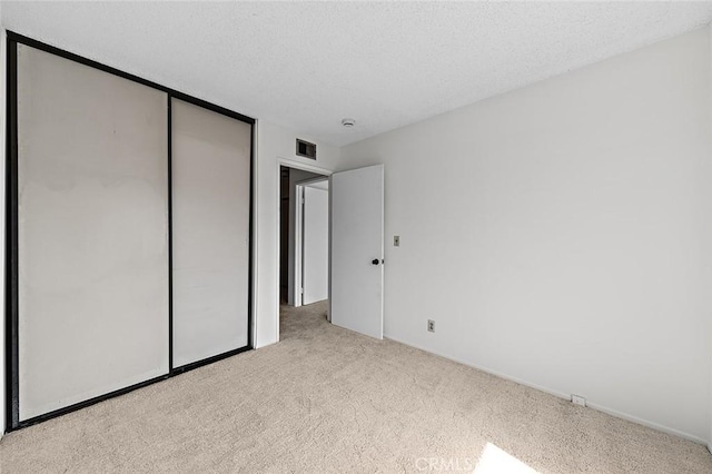 unfurnished bedroom with visible vents, carpet, a closet, and a textured ceiling