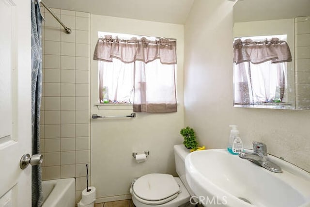 bathroom with toilet, shower / bath combo with shower curtain, and a sink