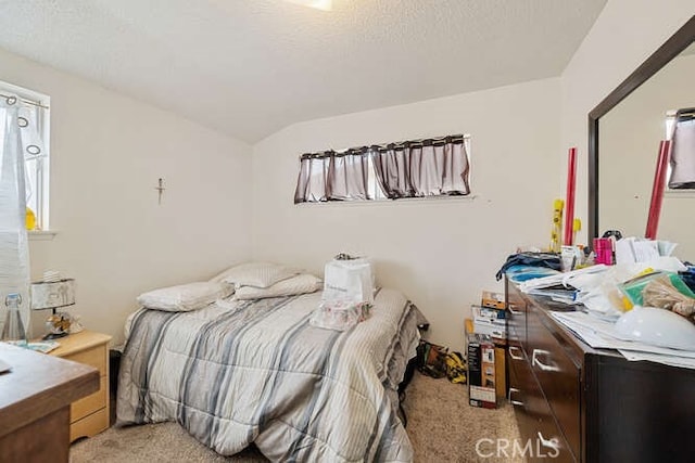 bedroom with a textured ceiling, vaulted ceiling, and light carpet