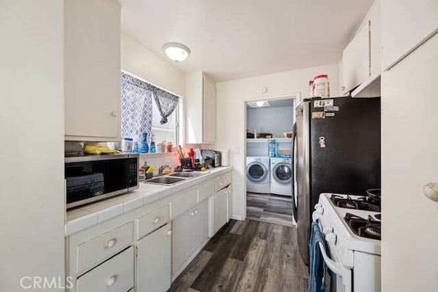 kitchen with washer and dryer, a sink, white cabinets, white range with gas stovetop, and tile counters