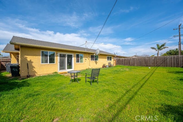 back of property with a yard, fence private yard, and stucco siding