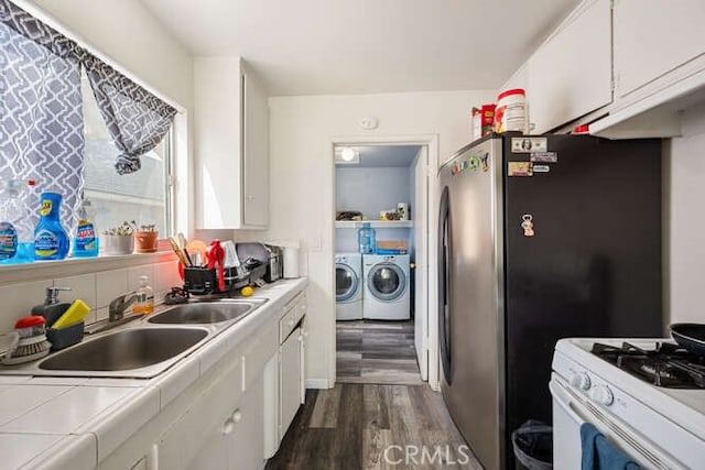 kitchen with separate washer and dryer, a sink, tile counters, white cabinets, and white gas range oven