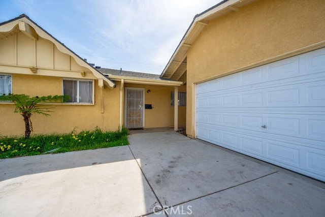 property entrance featuring concrete driveway and stucco siding