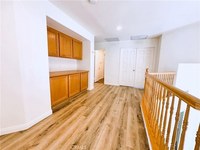 hallway with visible vents, baseboards, and light wood-style flooring