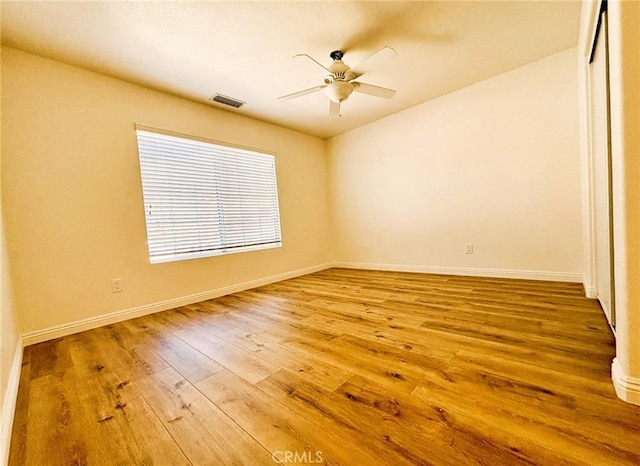 spare room with visible vents, wood-type flooring, baseboards, and ceiling fan