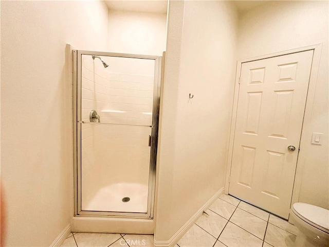 full bath featuring tile patterned floors, a shower stall, toilet, and baseboards