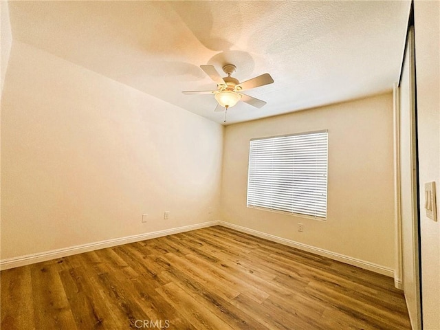 unfurnished room featuring a textured ceiling, baseboards, a ceiling fan, and wood finished floors