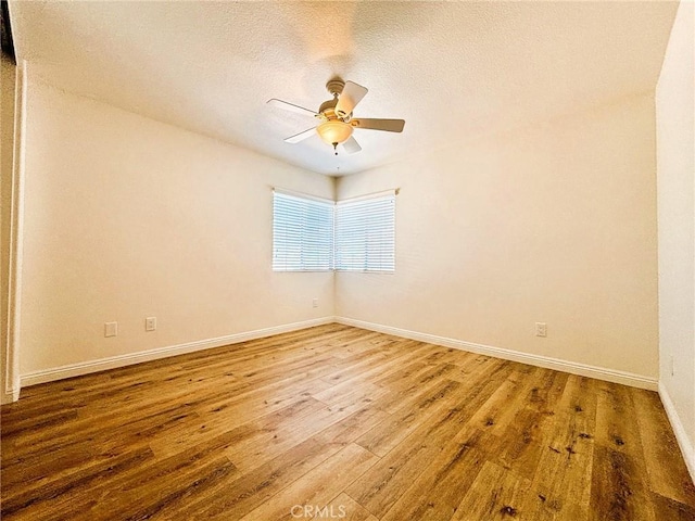 empty room featuring hardwood / wood-style floors, a textured ceiling, baseboards, and ceiling fan